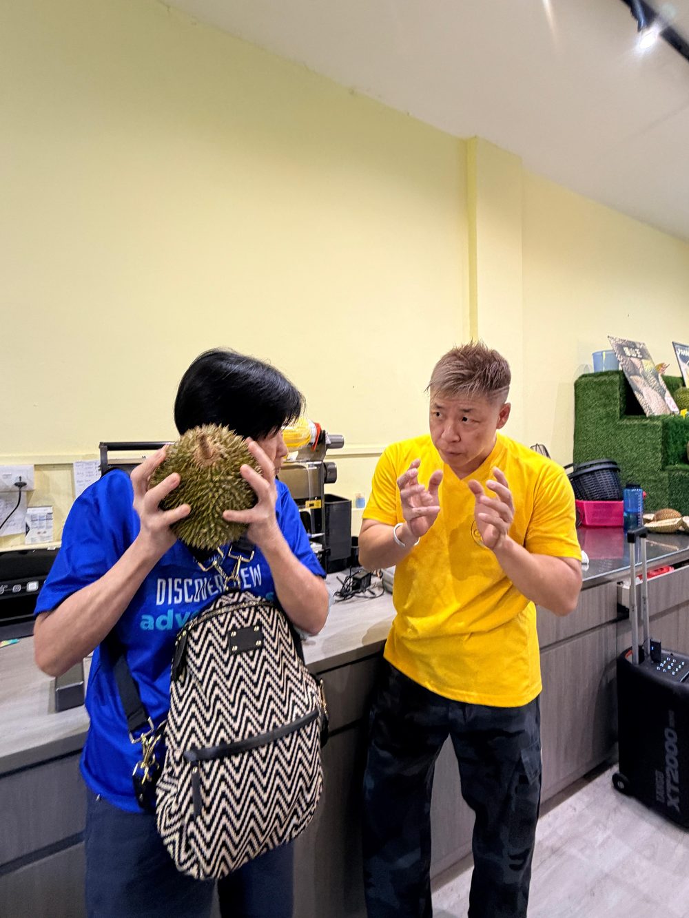 A facilitator guiding a senior participant as she examines and smells a durian