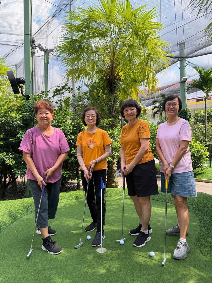 Grandparents and grandchildren playing mini-golf together at Dino Putt