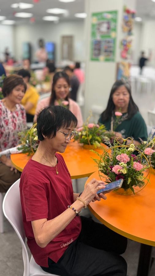 Seniors seated around flower arrangements with hanging hoop baskets at Edufarm's flower workshop