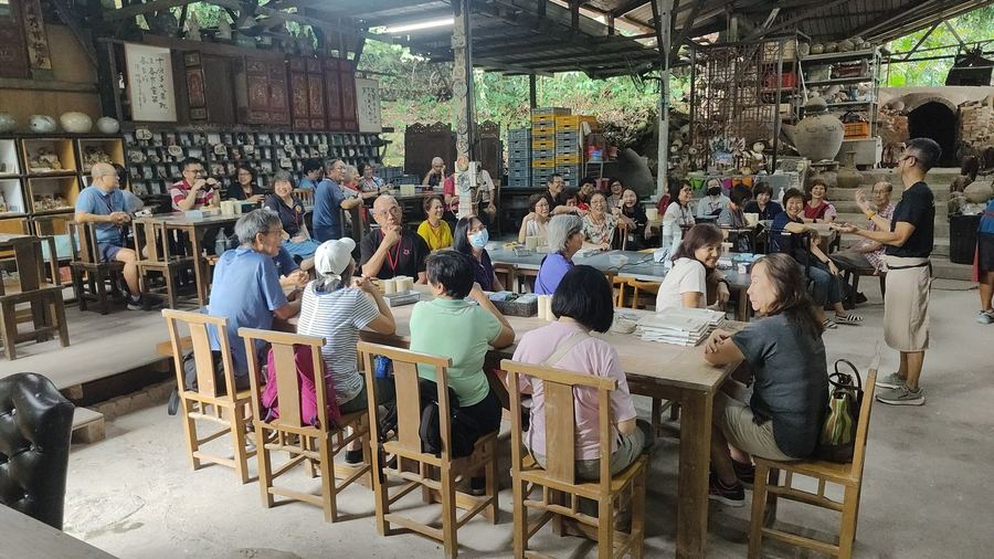 Seniors seated around the Dragon Kiln at Thow Kwang Pottery Jungle during a heritage pottery outing