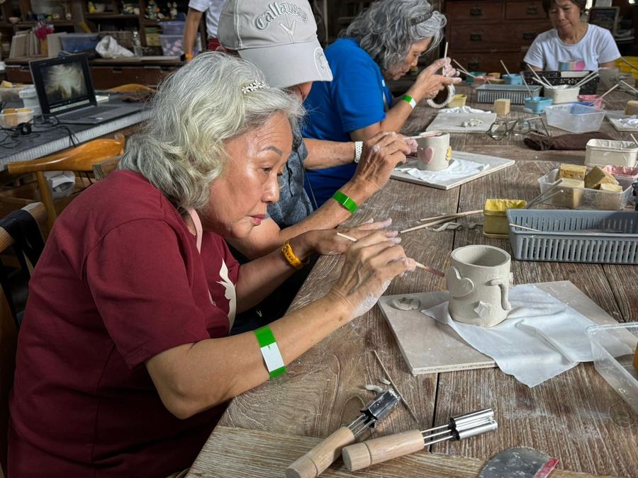 Seniors handbuilding clay mugs at a pottery workshop table at Thow Kwang Pottery Jungle