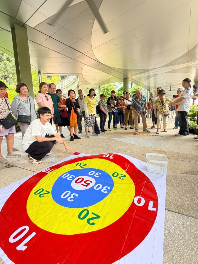 A large seniors group taking part in a giant bean-bag target toss team challenge on Sentosa