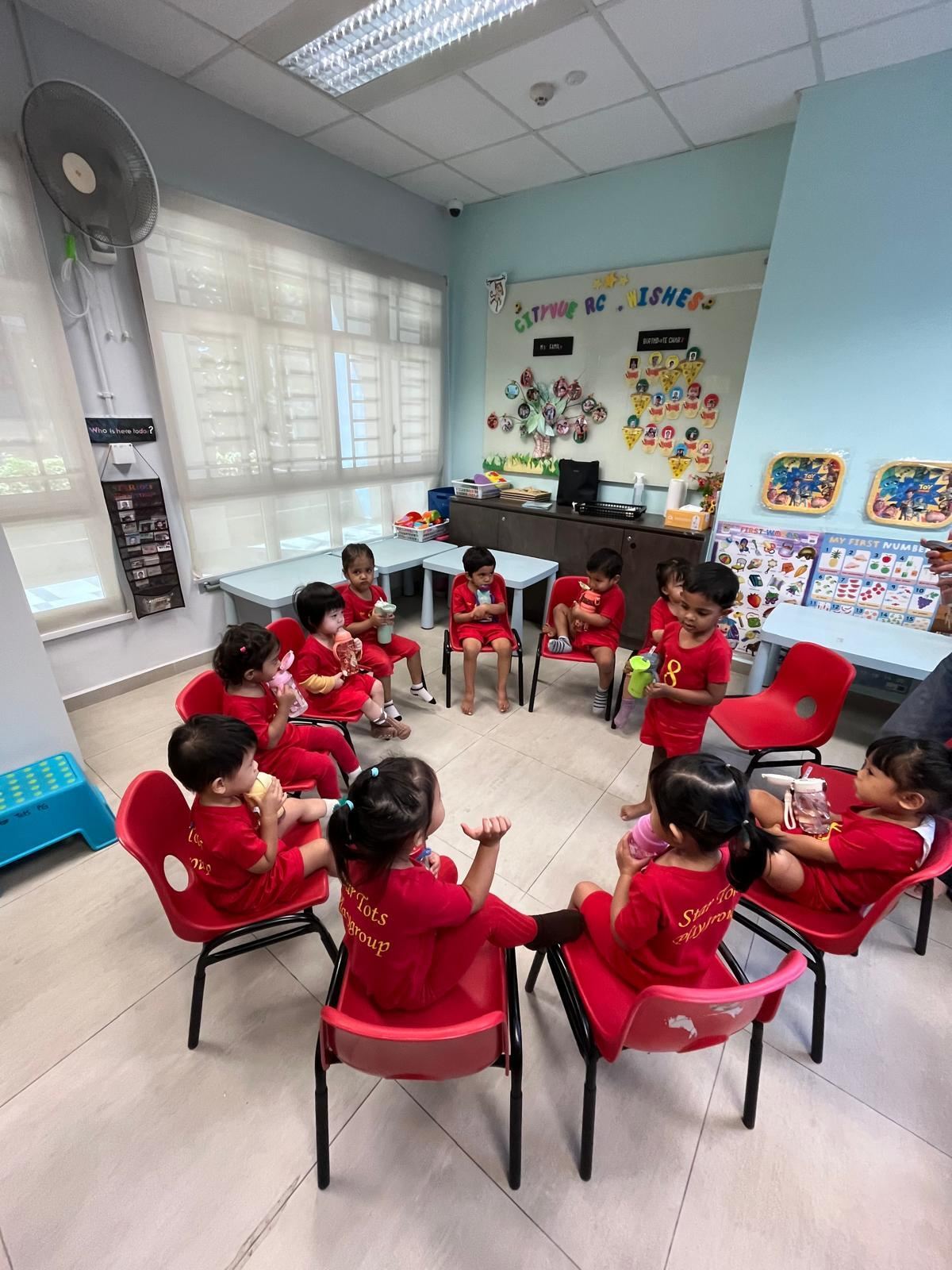 Star Tots children in red uniforms enjoying circle time together in a bright classroom